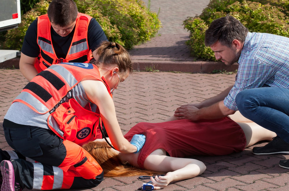 Couple of paramedics examining woman on the street