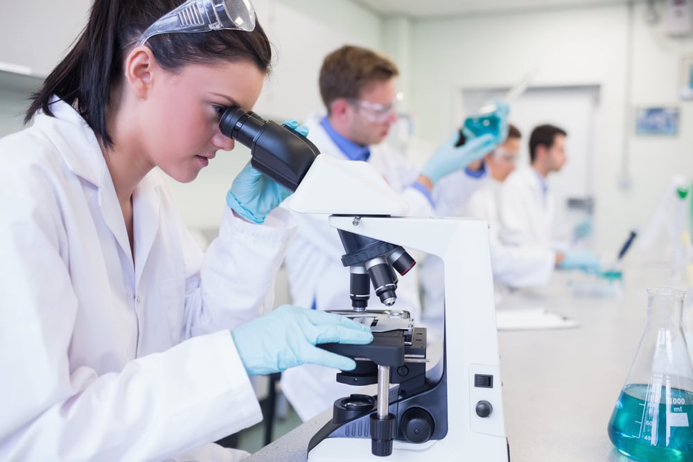Researcher in a white coat works intently with a microscope in the laboratory.